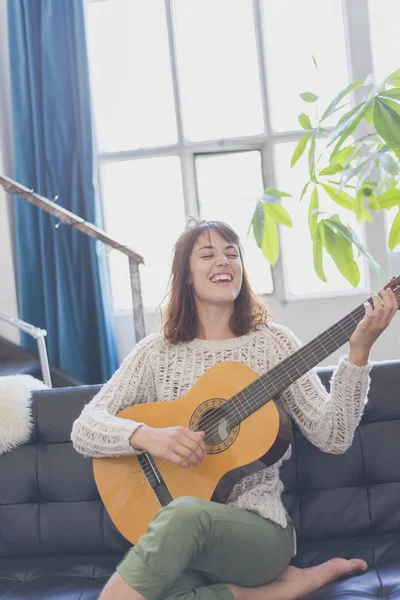 Gitar çalmak koltukta oturan güzel genç kadın