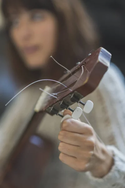 Belle jeune femme assise sur un canapé jouant de la guitare — Photo