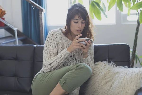 Una mujer sentada en el sofá, mirando hacia adelante y sonriendo — Foto de Stock