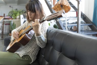 Bir dofa üzerinde oturan ve gitar çalmak güzellik kadın