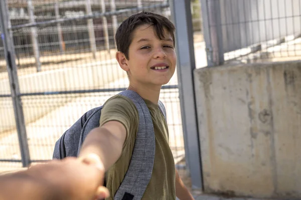 Onun sırt çantası ayakta okulun önünde taşıyan çocuk