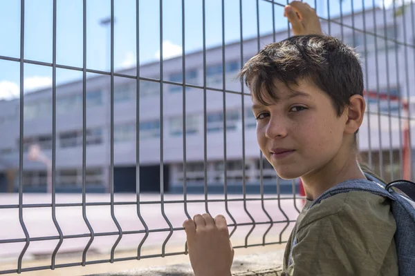 Onun sırt çantası ayakta okulun önünde taşıyan çocuk