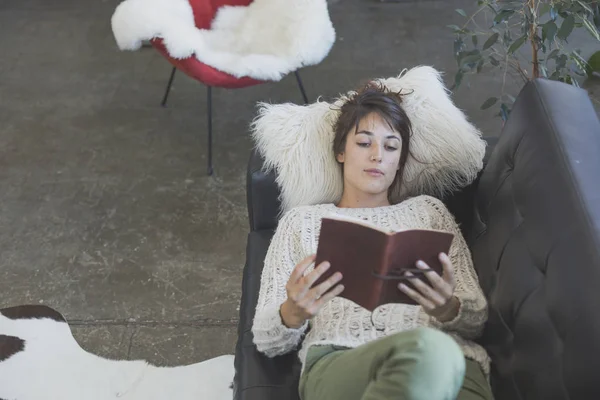 Frau liegt auf dem Sofa und liest ein Buch — Stockfoto