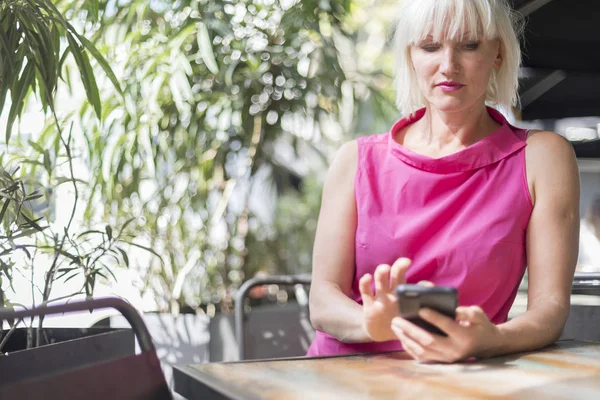Cep telefonu açık havada kullanan olgun sarışın kadın