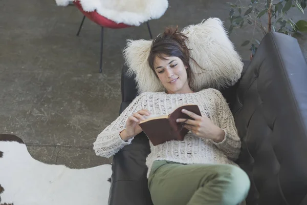 Žena ležela na pohovce a čtení knihy — Stock fotografie