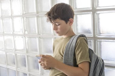 Okul üzerinde dinlenme ve bir cep telefonu ile oynarken öğrenci