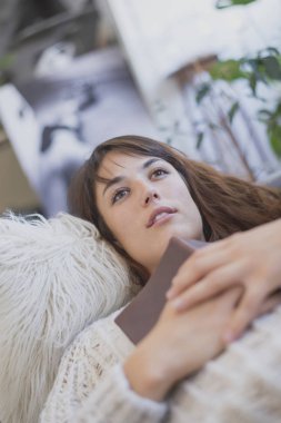 Yorgun genç kadın kanepede bir kitapla ona c arasında yalan yalan