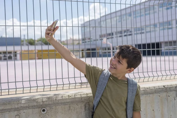 Schüler rastet vor einer Schule aus und spielt mit einem Handy — Stockfoto
