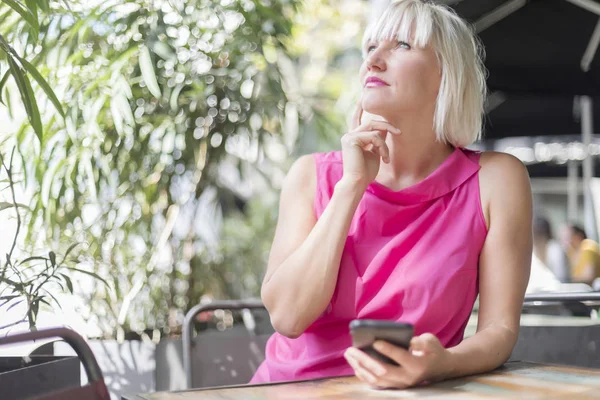 Cep telefonu açık havada kullanan olgun sarışın kadın