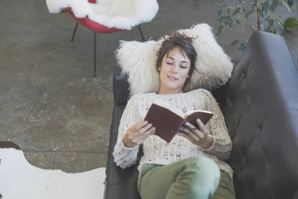 Frau liegt auf dem Sofa und liest ein Buch — Stockfoto