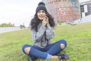 Kadınla çimenlerin üzerinde oturan telefon arama