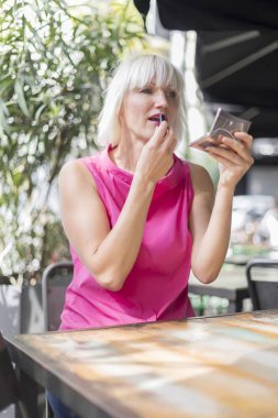 Güzel sarışın kadın bir gümüş ayna - sıklıkta kullanarak yapma