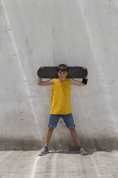 En tonårig pojke bär skateboard och ler — Stockfoto