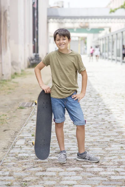 Un adolescente llevando monopatín y sonriendo — Foto de Stock