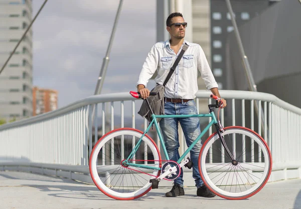 Een jonge stijlvolle man met zonnebril poseren naast zijn fiets. — Stockfoto