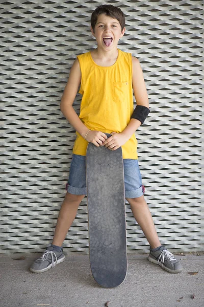 Un ragazzo adolescente che trasporta skateboard e sorride — Foto Stock