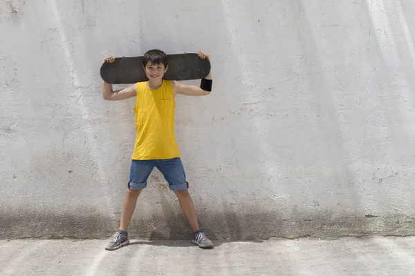 Un ragazzo adolescente che trasporta skateboard e sorride — Foto Stock