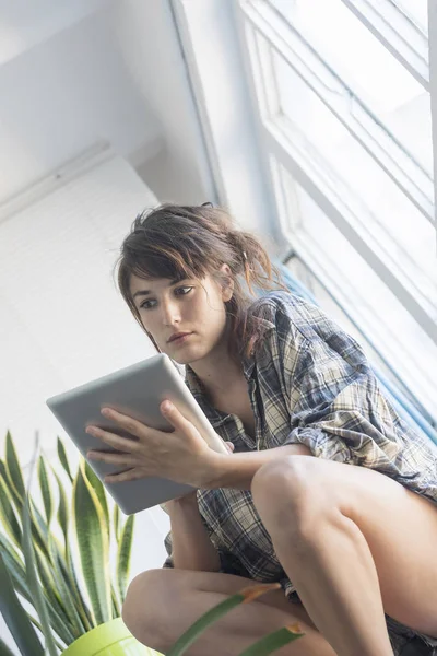 Woman on house stairs relaxing, reading email on a tablet