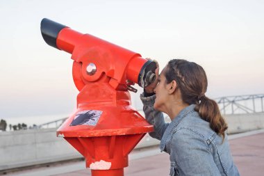 Genç kadın turist teleskopla bakarak