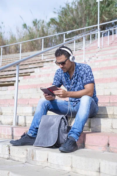 Müzik dinleme ve merdivenlerde oturan telefon yazarak mutlu çekici adam