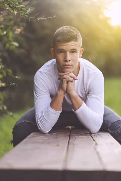 Adolescente elegante sentado en un banco de madera en un parque de la ciudad —  Fotos de Stock