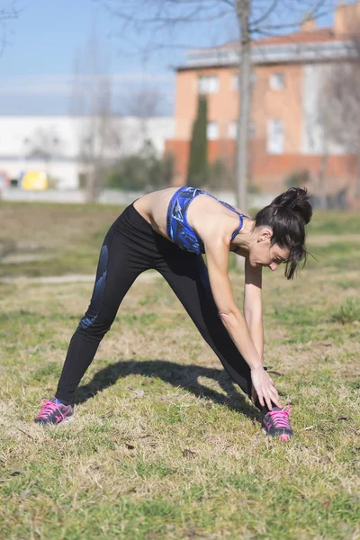 Kvinnan utför stretching innan jogging i en park — Stockfoto