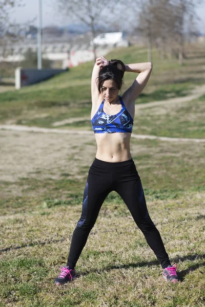 Kvinnan utför stretching innan jogging i en park — Stockfoto