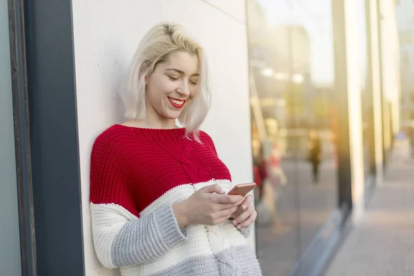 Schöne Frau schreibt eine Nachricht auf ihr Handy, während sie shopp macht — Stockfoto