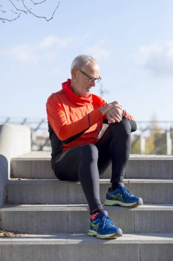 Kıdemli koşucu adam parkta onun exerc izleme sırasında dinlenme
