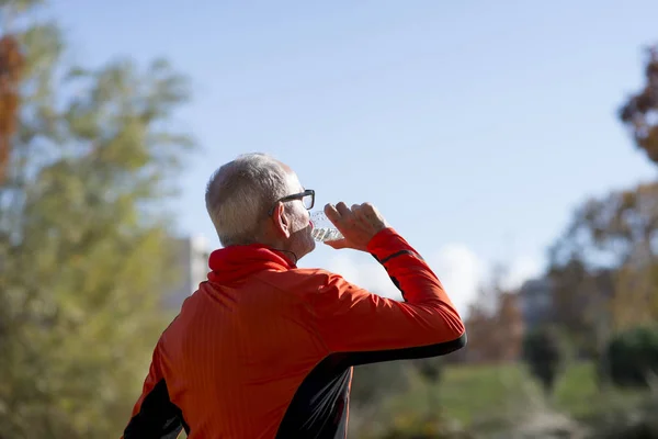 Senior runner drinking water after jogging