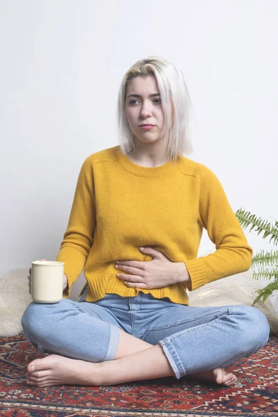 Ξανθιά γυναίκα κάθεται ταλαιπωρία στομαχόπονος — Φωτογραφία Αρχείου