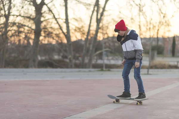 Skater-tiener dragen van een hoed instappen op straat — Stockfoto
