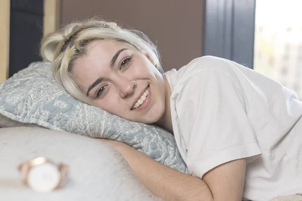 Una hermosa mujer feliz contenido acostada en la cama sonriendo a la cámara . — Foto de Stock