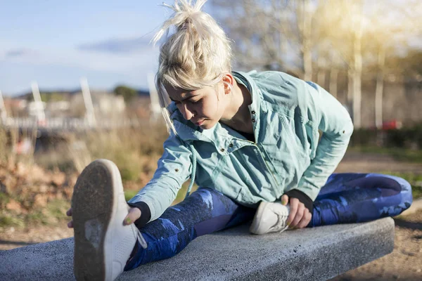 En vacker ung blond kvinna stretching utomhus — Stockfoto