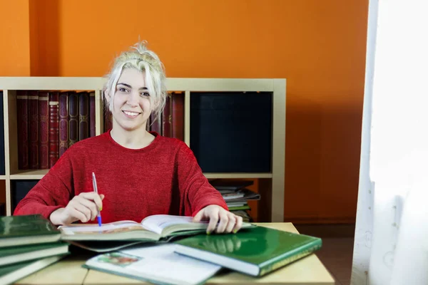 Student szczęśliwy uśmiechający się podczas studiów i patrząc na kamery — Zdjęcie stockowe