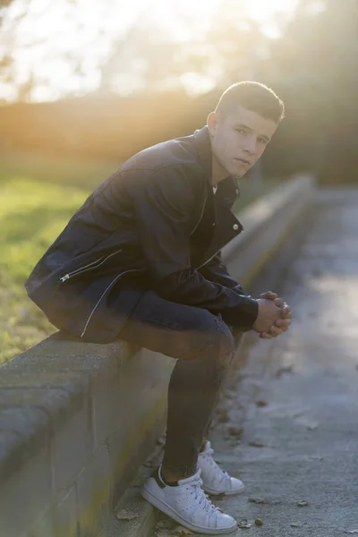 Elegante joven en chaqueta de cuero mirando a la cámara, sentado i —  Fotos de Stock