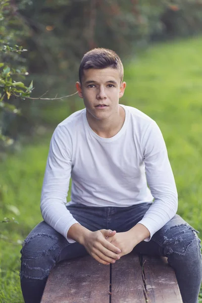 Adolescente elegante sentado en un banco de madera en un parque de la ciudad —  Fotos de Stock