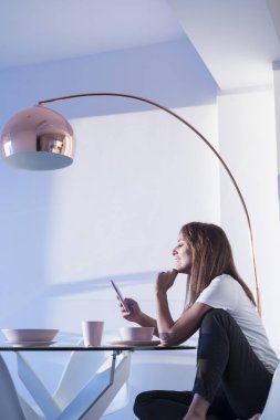Attractive adult woman sitting at living room while using mobile phone