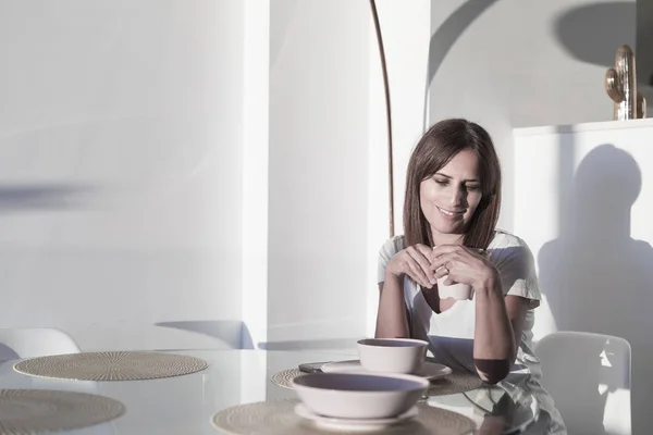 Mujer de pelo largo sentada en el salón mientras sostiene una taza de té — Foto de Stock