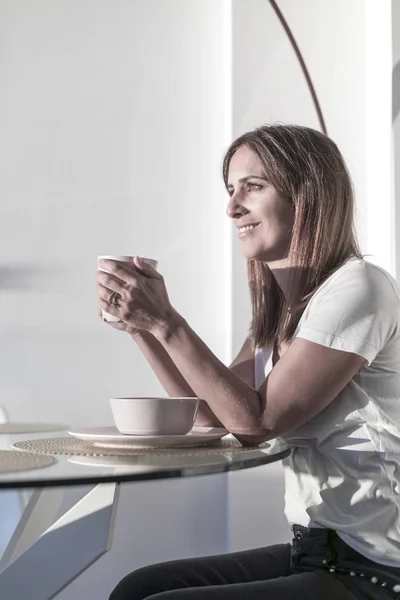 Mujer de pelo largo sentada en el salón mientras sostiene una taza de té — Foto de Stock