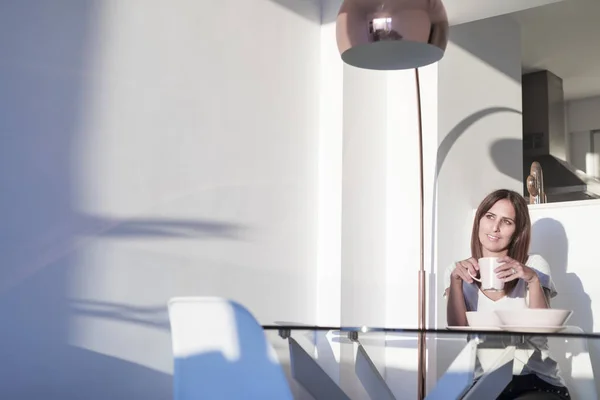 Mujer de pelo largo sentada en el salón mientras sostiene una taza de té —  Fotos de Stock