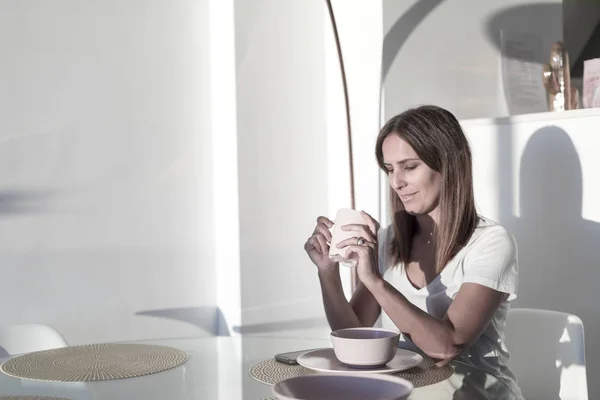 Mujer de pelo largo sentada en el salón mientras sostiene una taza de té —  Fotos de Stock