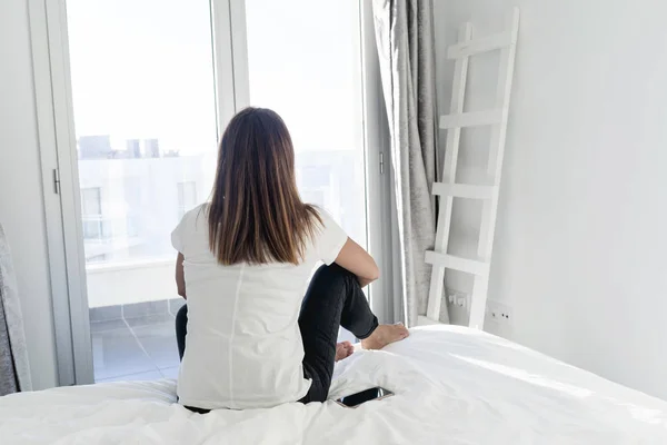 Vista trasera de una mujer adulta relajante sentada en la cama —  Fotos de Stock