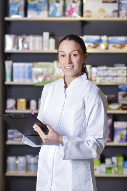 Neşeli kadın eczacı ayakta dururken notlar alıyor