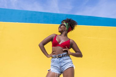 Eğlenceli genç Afro-Amerikalı kadın dışarıda gülüyor ve dans ediyor.