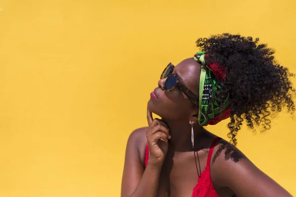 Vista lateral de uma mulher afro com óculos de sol olhando para o lado pensativo — Fotografia de Stock