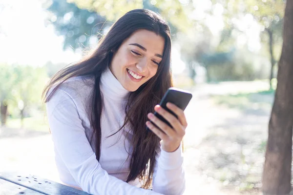 Porträt einer hispanischen jungen Frau mit Handy im Park an sonnigen Tagen lächelnd - sehr glückliche Frau auf dem Handy — Stockfoto