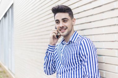 Sokakta cep telefonunu kullanırken dışarıda duran yakışıklı genç adamın portresi..