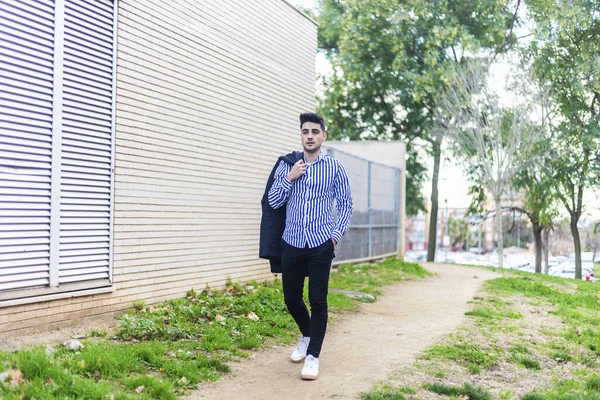 Jonge man met baard loopt rond in de stad met een jas aan. — Stockfoto