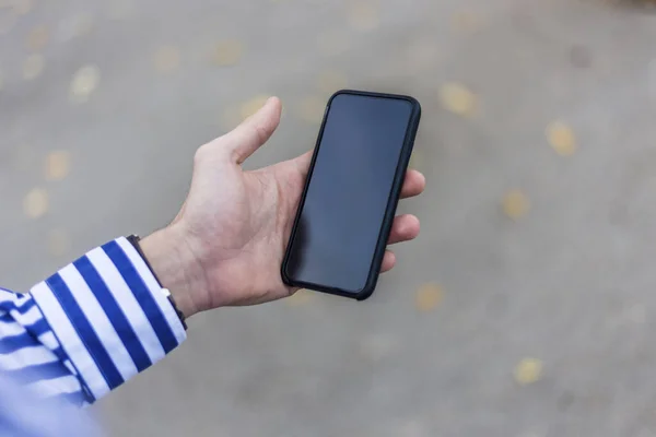 Jeune homme avec smartphone à la main textos en plein air dans la rue — Photo